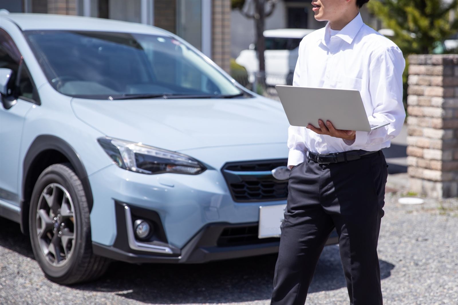 ノートPCを手に車両をチェックする査定士
